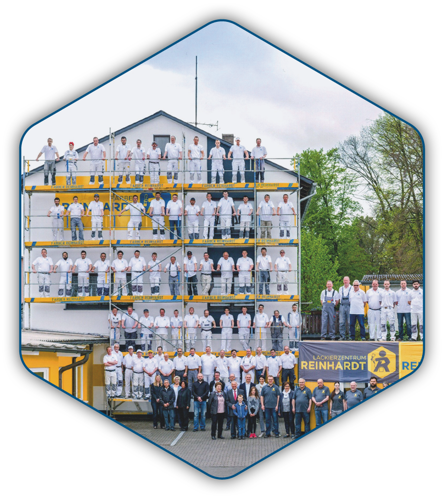 Gruppenbild der gesamten Belegschaft auf einem Gerüst vor dem Firmengebäude in Stadtallendorf