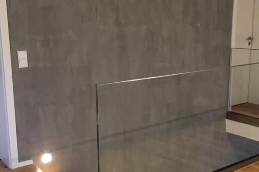 Ansicht eines Treppenabgangs mit veredelter Oberfläche der Wand in Betonoptik und Glasabtrennung