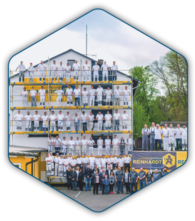Gruppenbild der gesamten Belegschaft auf einem Gerüst vor dem Firmengebäude in Stadtallendorf