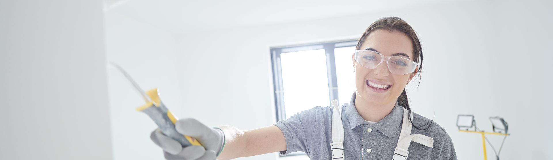 Weibliche Person steht in einem hellen Raum und lacht in die Kamera und ist erkennbar als Malerin identifizierbar