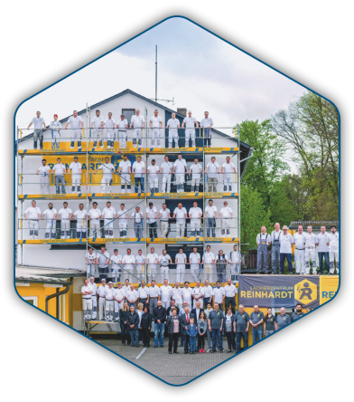 Gruppenbild der gesamten Belegschaft auf einem Gerüst vor dem Firmengebäude in Stadtallendorf